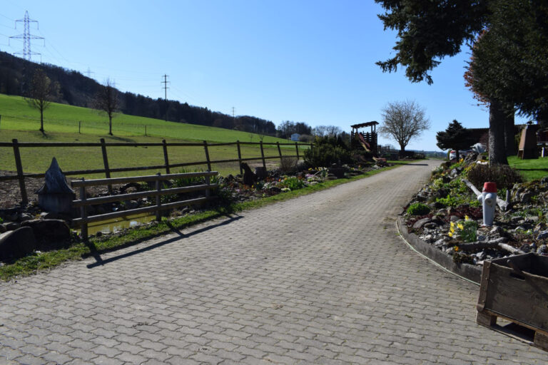 Hofeinfahrt, links Pferdeweide, rechts Garten